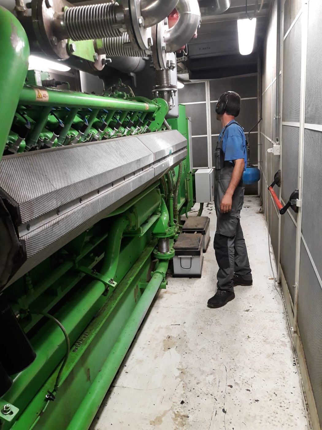 Tecnico accanto a un cogeneratore a gas dentro il container