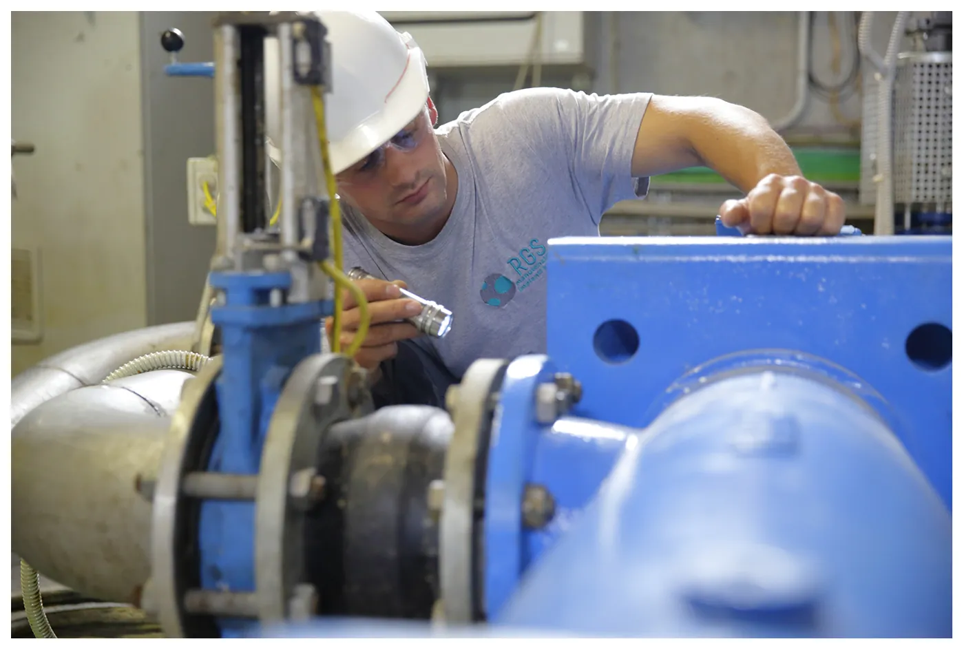 Tecnico RGS con il casco controlla una pompa della linea di carico dell'impianto